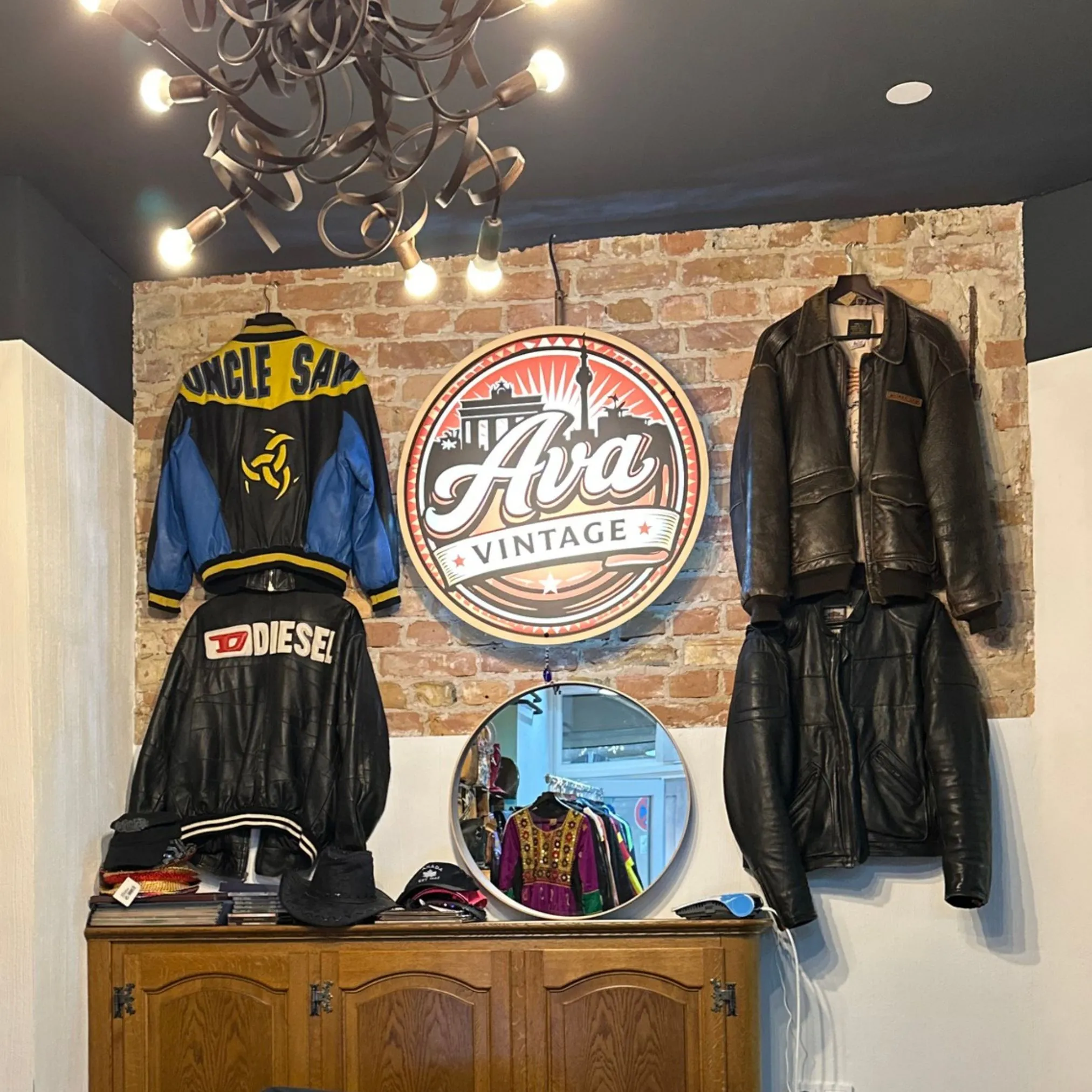 Wand mit dem Ava-Vintage-Logo, daneben Vintage-Sportjacken und Lederjacken